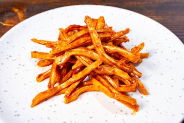 Parlak renkli domuz kulakları beyaz bir tabakta düzgünce istiflenmiştir. Çanak, ahşap zeminli hoş bir zıtlık sergiliyor, canlı çekiciliğini vurguluyor..