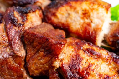 Sulu ızgara et parçaları canlı yeşil marulun yanında sunuluyor. Bu yaz barbekü partisi sergileniyor. Dışarıda arkadaşlarınız ve ailenizle çok lezzetli yemekler yiyorsunuz..