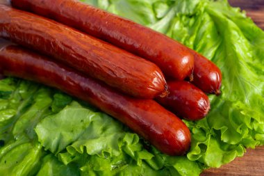 Dört sulu sosis canlı yeşil marul yaprakları üzerinde güzelce düzenlenir, zengin renklerini ve taze görünüşlerini ön plana çıkarırlar. Kurulum lezzetli bir yemek hazırlığı öneriyor..