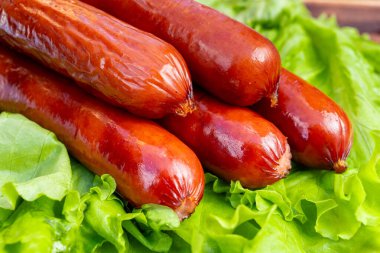 Sulu sosisler canlı yeşil marul yapraklarının üzerine güzelce dizilir. Zengin renklerini ve iştah açıcı parıltılarını vurgularlar. Ayarlar taze ve davetkar bir yemek olduğunu gösteriyor..