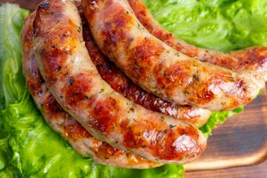 Sulu sosisler ustalıkla altın kahverengiye pişirilir ve canlı yeşil marul yapraklarına yerleştirilir. Yemek çok cazip bir sunum sunuyor. Yaz barbeküsü için mükemmel..