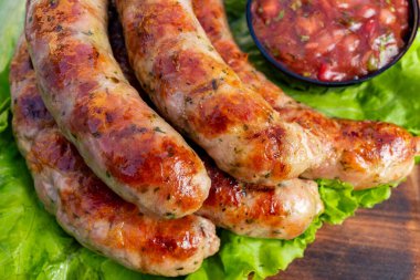 Sulu ızgara sosisler canlı bir marul yatağında ayarlanır. Renkli bir salsa sosu lezzeti arttırır ve yaz için mükemmel hale getirir..