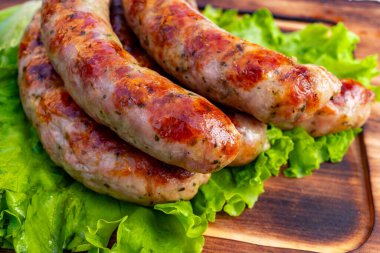 Dolgun, ızgara sosisler canlı yeşil marul yatağı üzerine dizilir. Sosisler altın-kahverengiye sahip, nefis pişmiş bir dış görünüşü sergiliyorlar yaz yemeği için mükemmel..