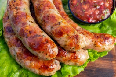 Sulu ızgara sosisler canlı bir marul yatağında ayarlanır. Renkli bir salsa sosu lezzeti arttırır ve yaz için mükemmel hale getirir..