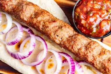 Ağız sulandıran kebap, kırmızı soğan dilimleriyle çevrili ve yanında bir kase taze salsa sosu ile sıcak ekmek üzerine konur. Bu nefis yemek nefis bir yemek için mükemmel..