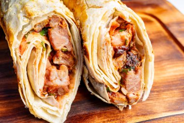 İki doyurucu paket, ahşap bir yüzeye güzelce sarılıp dinlenen ızgara et ve çıtır çıtır sebzelerin karışımı lezzetli bir lezzet deneyimini davet ediyor..