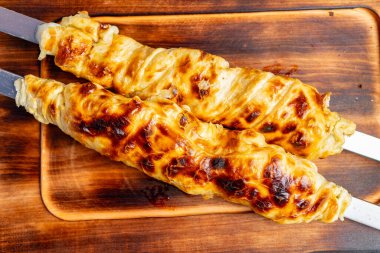 Lezzetli kebaplar, güzel bir altın-kahverengiyi gösteren açık bir alevin üzerinde mükemmel bir şekilde kızartılıyor. Bu açık hava mutfağı yemek hazırlıklarına kırsal bir cazibe katıyor..