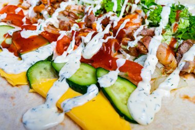 Canlı bir paket, ızgara tavuk, taze marul, domates, salatalık ve sos katmanları içerir. Renkli malzemeler, tadını çıkarmaya hazır iştah açıcı bir yemek yaratır..