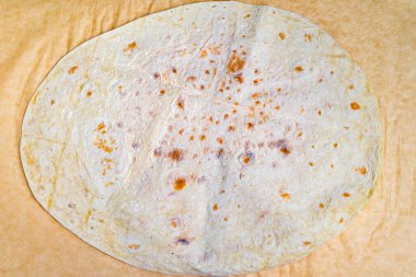 Büyük, yuvarlak bir ekmek pürüzsüz bir tezgahın üzerinde duruyor, dokusunu ve yüzeyini sergiliyor. Ekmek taze görünüyor, çeşitli malzemeler ve malzemelerin eklenmesi için hazır..