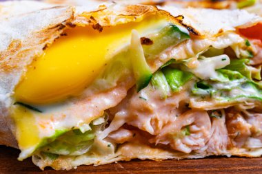 Taze tavuk, taze marul, kremalı sos ve erimiş peynirle dolu lezzetli bir tavuk dürümü. Paket mükemmel kızartılmış, canlı renkler ve dokular sergileniyor..