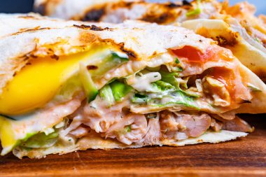 Bu yemek somon, yumurta ve taze sebzelerle dolu lezzetli bir dürüm sergiliyor. Malzemeler ustalıkla katmanlanmış, lezzet ve dokuların karışımını vurguluyor..