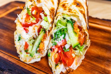 Lezzetli bir ızgara ambalajında taze sebzeler, domatesler, salatalıklar ve marul gibi canlı katmanlar sergileniyor..