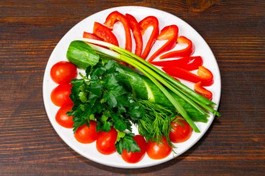 Tabaktaki canlı taze sebzeler arasında kırmızı dolma biber, kiraz domatesleri, salatalık, yeşil soğan ve doğranmış otlar yer alıyor..