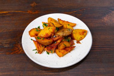 Bir tabak altın kahverengidir, kıtır kıtır baharatlı patates kamışı, doğranmış otlarla süslenir. Kırsal ahşap arka plan bu yemeğin iştah açıcı görünümünü arttırır..