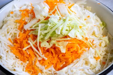 İnce doğranmış lahana, havuç ve yeşil soğanla dolu bir kase. Renkli karışım sağlıklı salata ya da lahana salatasına hazırlık olduğunu gösteriyor. Hafif bir yemek için mükemmel..