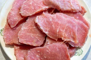 Tabakta düzgünce düzenlenmiş taze domuz dilimleri sergileniyor, etin dokusunu ve kalitesini gözler önüne seriyor. Ev yemeklerinde çeşitli tarifler için idealdir..