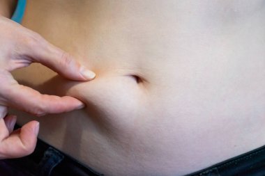 Bir el nazikçe insanın karnına bastırır, derisine ve altında yatan dokuya odaklanır. Bu eylem vücut gerilimi ve gevşeme seviyelerinin değerlendirilmesini gösterir.