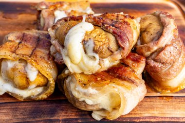 Sulu ızgara köfteler ahşap bir tahtaya istiflenmiş, her biri erimiş peynirle dolmuş. Renkler ve dokular toplanmak için mükemmel lezzetli ve doyurucu bir yemeği vurguluyor..