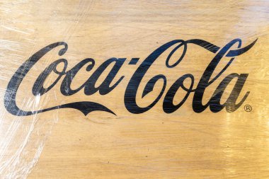 Tahta levhada iyi bilinen bir içecek amblemi var. Plastik ambalajla kısmen gizlenmiş. Vinnytsia, Ukrayna - 05.03.2025