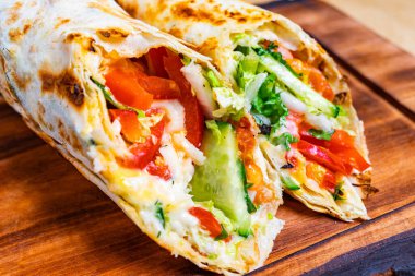 Lezzetli bir ambalajda taze domatesler, salatalıklar ve marul sergileniyor. Tereyağından kıl çeker gibi sıcacık bir tortilla ile sarılmış. Öğle yemeği ya da hafif akşam yemeği için mükemmel..