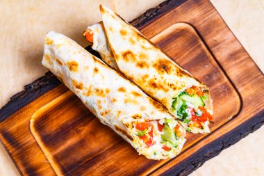 Salata, domates ve salatalık gibi rengarenk taze sebzelerle dolu ahşap bir tahtanın üzerinde iki paket sergileniyor..