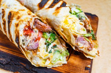 Taze ızgara burritolar lezzetli et, sebze ve kremalı soslarla doludur. Tahtada çok güzel sunuluyorlar. Canlı renkler ve dokular sergiliyorlar..