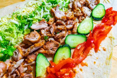 Taze ızgara tavuk, kıtır kıtır marul, salatalık ve biberin yanında dilimlenmiş ve katmanlanmış. Renkli ve iştah açıcı bir yemek oluşturuyor..