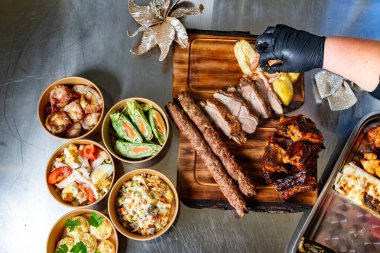 Bir masada ızgara et ve renkli kenarlardan oluşan bir ziyafet düzenlenir. Sulu barbekü kaburgaları, şişler ve taze salatalar bir aile toplantısı için davetkar bir ortam yaratır..