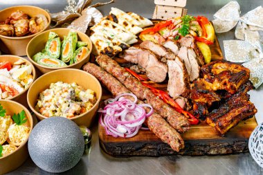 Renkli aperatifler ve salataların yanında sosis ve tavuk da dahil olmak üzere canlı bir ızgara et çeşidi servis ediliyor. Gösteri şenlikli, kutlama için mükemmel..