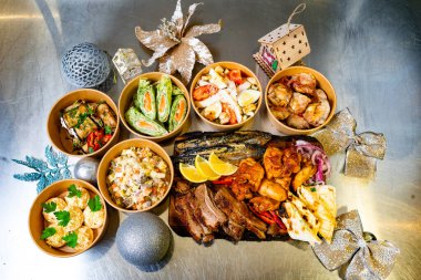 Güzelce sunulmuş bir dizi yemek, şenlikli bir toplantının keyfini bekliyor. Masada çeşitli et, salata ve pirinçler, neşeli bir atmosferde canlı renkler ve dokular sergileniyor..