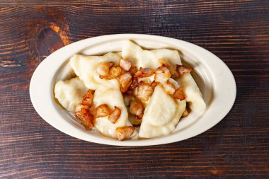 Lezzetli malzemelerle dolu lezzetli hamur köfteleri gevrek pastırma parçalarıyla süslenmiş bir kasede servis edilir. Bu yemek en iyi yemeklerinden birini sergiliyor..