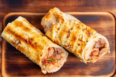 Lezzetli hamur işleri taze pişmiş, altın kahverengidir ve lezzetli et ve sebzelerle doludur. Köy ahşap bir tahtaya kurulurlar, eğlenmeye hazırdırlar..