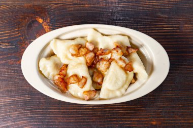 Lezzetli malzemelerle dolu lezzetli hamur köfteleri gevrek pastırma parçalarıyla süslenmiş bir kasede servis edilir. Bu yemek en iyi yemeklerinden birini sergiliyor..