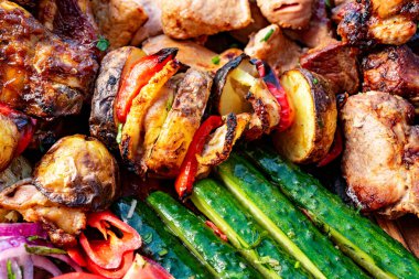 Açık hava barbeküsünde rengarenk bir ızgara et ve sebze çeşidi sunuluyor. Sulu tavuk ve sığır eti canlı biber, kabak ve soğanla eşleştirilir..