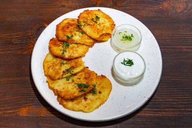 Patatesli krepler taze otlarla süslenmiş yuvarlak bir tabakta güzelce düzenlenir. İki küçük kase kremalı sos, lezzeti arttırmak için yemeğe eşlik eder..