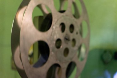 Kürsüde dinlenen klasik bir film makarasının yakın çekimi. Makara, film çekme ve nostalji sanatını sembolize eden, rustik bir metal kaplama ve karmaşık ayrıntılar sergiliyor..