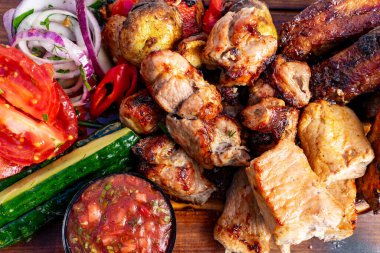 Renkli bir tabakta çeşitli ızgara etlerin yanı sıra taze domates, salatalık, soğan ve küçük bir kase salsa sosu yer alır. Yaz barbeküsü ya da aile toplantısı için mükemmel..