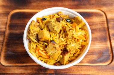 Bu yemek yumuşak et, canlı sebzeler ve baharatlarla karıştırılmış aromatik pirinç dolu bir kase içeriyor, sade ahşap bir yüzeyde güzelce sıralanmış. Her durum için mükemmel bir yemek..