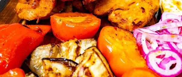 Sulu ızgara tavuk ve dolmalık biber, domates ve patlıcan gibi renkli sebzeler, canlı ve iştah açıcı bir yemek sergilenen rustik ahşap bir tabakta düzenlenir..