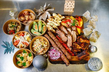 Canlı bir ızgara et çeşidi, taze salatalar ve ahşap bir tabakta güzel bir şekilde düzenlenmiş lezzetli kenarları. Bu kutlama yemeği toplantılar ve özel durumlar için mükemmeldir..