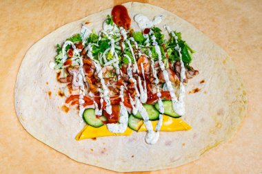 Izgara tavuk, taze sebze ve sosla hazırlanmış renkli bir paket yemek tezgahındaki tezgahta sergileniyor. Canlı bileşenler yemeğin iştah açıcı doğasını vurgular..