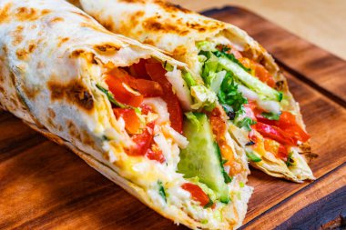 Lezzetli bir sargı sergileniyor, renkli sebze ve tavuk katmanları sergileniyor. Taze malzemeler canlı tatları vurgular, hızlı bir yemek veya atıştırmalık için mükemmeldir..