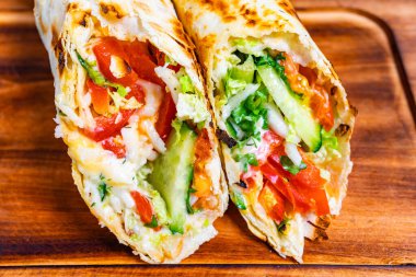 Marul, domates ve salatalık gibi rengarenk malzemelerle süslenmiş iki parça ekmek. Bu yemek hızlı bir öğle yemeği ya da atıştırmalık için mükemmel. Tazelik ve lezzeti vurguluyor..