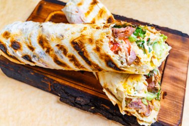 Tahta bir tahtanın üzerinde doyurucu bir ızgara sergileniyor, taze sebzeler ve lezzetli etlerin renkli bir karışımını sergiliyor, iştah açıcı ve doyurucu yemekleri vurguluyor..