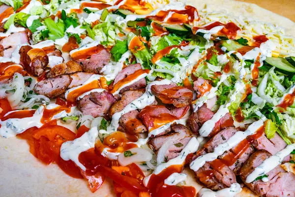 Izgara et, taze marul, salatalık ve sosla doldurulmuş büyük bir burrito öğle yemeği sırasında canlı bir sokak yiyecek standında hazırlanır..