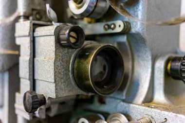 Bir film projektörünün iç çalışmalarını gösteren detaylı bir görüntü. Vitesler ve topuzlar görünür, ustalığı ve hassas mühendisliği yansıtır, projeksiyonun arkasındaki mekaniği vurgular..