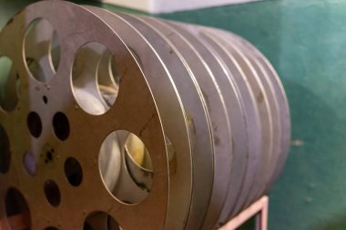 Metal film makaraları, klasik sinematografinin cazibesini yansıtan yeşil duvarlı bir depoda güzelce istiflenmiştir. Sinema yapımının ve izlemenin zengin tarihine dair ipuçları veriyorlar..