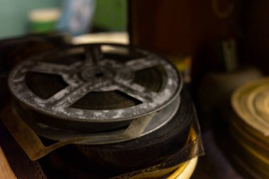 Tozlu film yığınları loş aydınlatılmış bir depoda dinleniyor ve zamanın nasıl geçtiğini gösteriyor. Makaraların boyutu ve durumu farklıdır, bu da içerideki zengin sinema tarihine işaret eder..