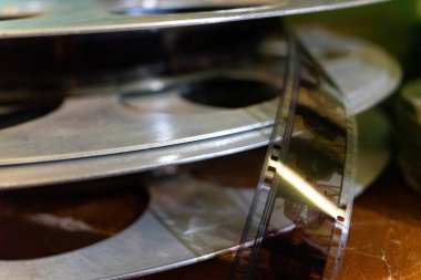 Eski film makaraları ahşap bir masaya dizilir, her makaranın dokularını ve detaylarını vurgular. Sahne klasik film yapımcılığının ve sinematik nostaljinin özünü yakalıyor..