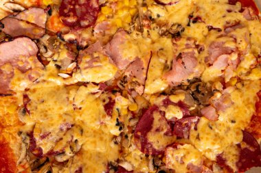 Jambon, salam, mantar ve mısırla dolu taze pişmiş bir pizza. Hepsi de yapışkan, altın peynirle kaplanmış. Kıtır kıtır bir kabukla mükemmel pişirilmiş, tadını çıkarmaya hazır..